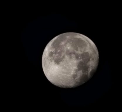 Full moon illuminated against a black sky, displaying surface details and craters.
